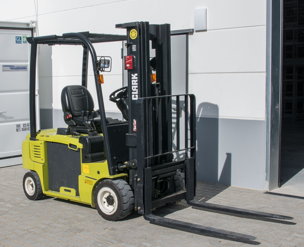 An image of a yellow forklift in front of a warehouse door. This warehouse handling equipment can operate inside and outside of the warehouse.